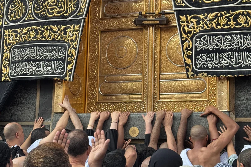 معتمرون يمدون أيديهم إلى باب الكعبة